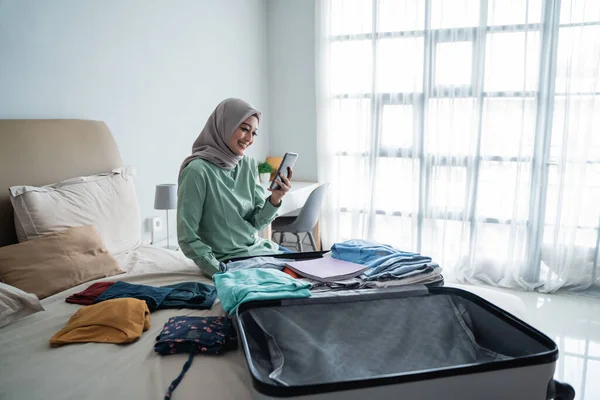 Азиатская мусульманка смотрит расписание вылета через мобильный телефон — стоковое фото
