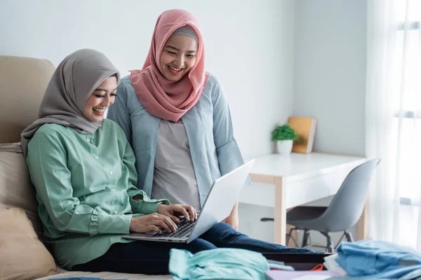 Zwei muslimische Frauen suchen per Online-Anwendung per Laptop nach Abflugplänen — Stockfoto