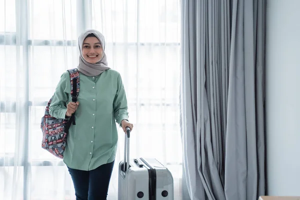 Glimlachende jonge hijab reiziger dragen haar tas en het houden van koffer — Stockfoto