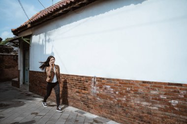 Kadın şehirde yürürken telefonla konuşuyor.