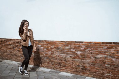 Kadın şehirde yürürken telefonla konuşuyor.