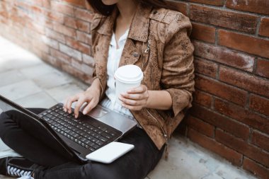 Kadın dışarıda çalışırken oturup kahvenin tadını çıkarıyor.