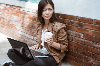 Kadın dışarıda çalışırken oturup kahvenin tadını çıkarıyor.