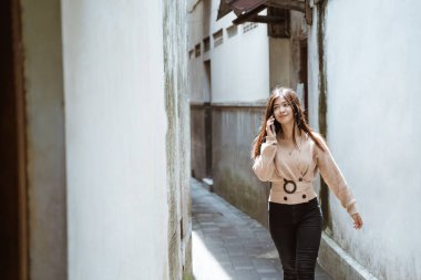 Kadın şehirde yürürken telefonla konuşuyor.