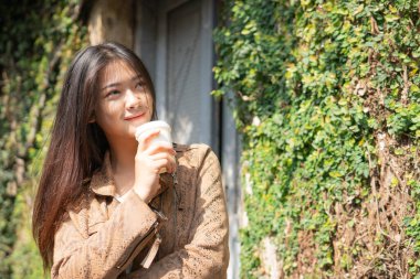 Bir fincan kahve içerken yürüyen bir kadın.