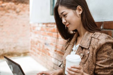 Kadın dışarıda çalışırken oturup kahvenin tadını çıkarıyor.
