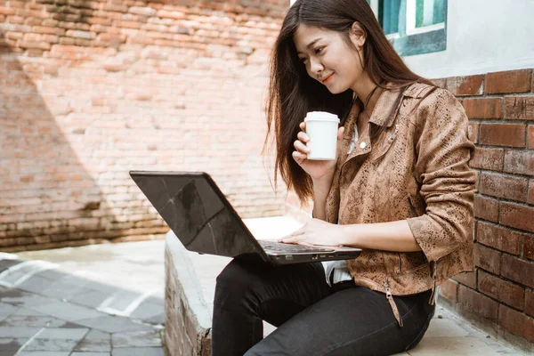 Kadın dışarıda çalışırken oturup kahvenin tadını çıkarıyor.