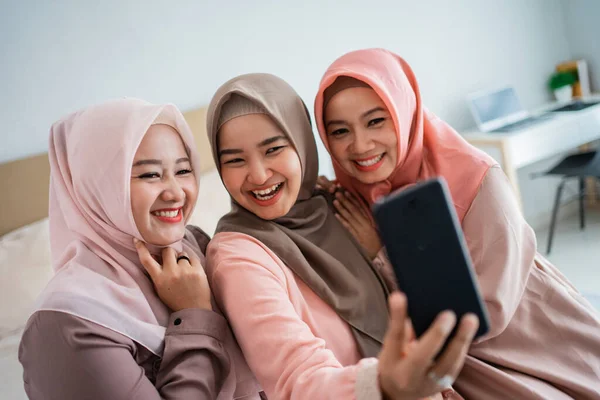 Drei verschleierte Frauen nutzen Smartphone für Fotos — Stockfoto