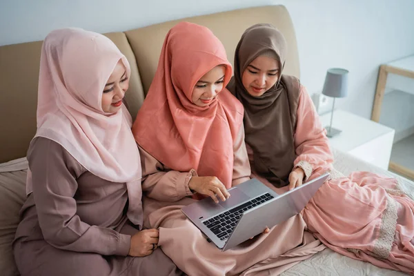 Mujeres musulmanas asiáticas que usan computadora portátil para buscar artículos en la tienda en línea cuando se quedan en casa — Foto de Stock