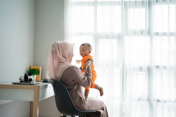 Ibu menggendong anaknya di pangkuan ketika bermain sambil duduk di kursi — Stok Foto