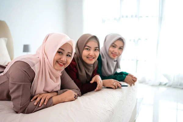 Tres asiático hijab mujer oliendo mirando la cámara cuando acostado en la cama — Foto de Stock