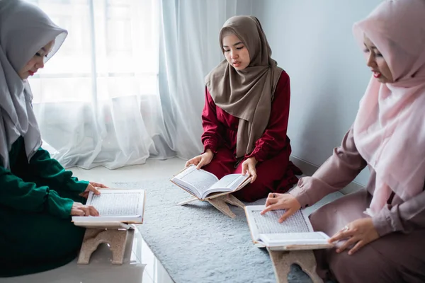 Drie Aziatische moslimvrouwen lezen en leren samen het heilige boek van de Al-Koran. — Stockfoto