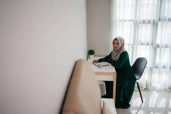 Asiatica hijab donne sorridenti quando sedersi sulla sedia di studio e la lettura del libro sacro di Al-Corano — Foto Stock