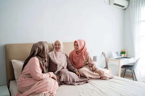 Группа мусульманских женщин, сидящих на кровати, наслаждаются общением — стоковое фото
