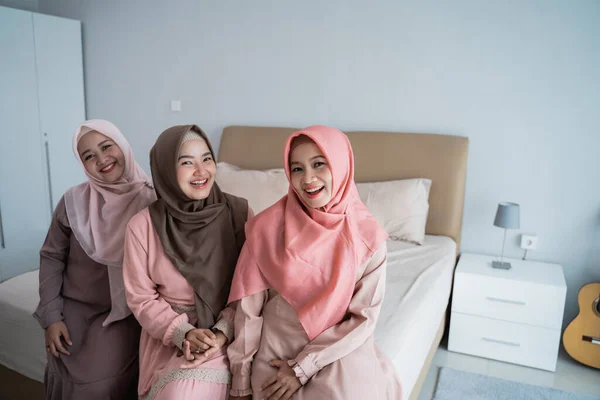 Sonriendo tres mujeres hijab sentadas en la cama en el dormitorio — Foto de Stock