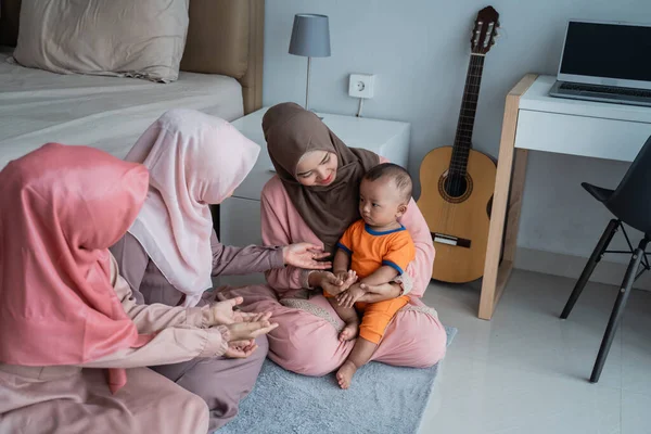 Азиатская мусульманская мать со своими друзьями нравится играть со своим сыном, когда сидит на полу — стоковое фото