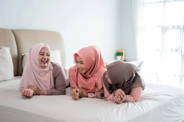 Tiga wanita jilbab berbaring di tempat tidur berbicara dan mengobrol bersama — Stok Foto