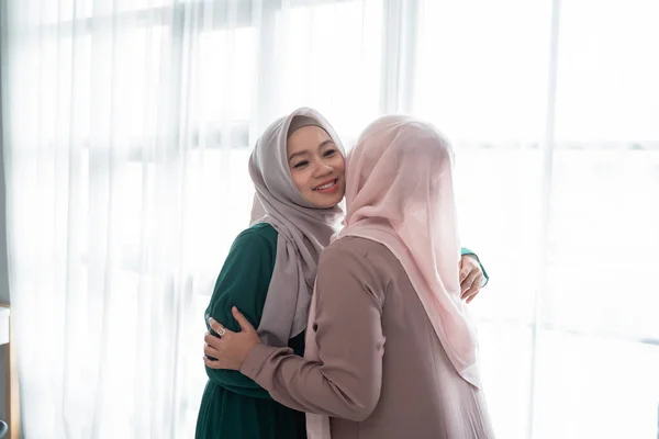 veiled woman hugs and kiss her sister when meeting