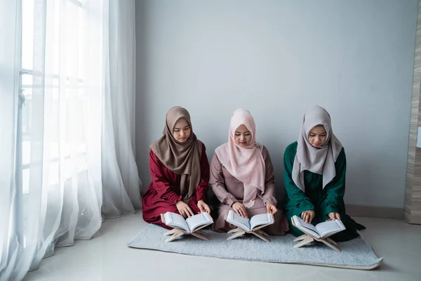 Три азиатских мусульманки читать и изучать священную книгу Аль-Корана вместе — стоковое фото