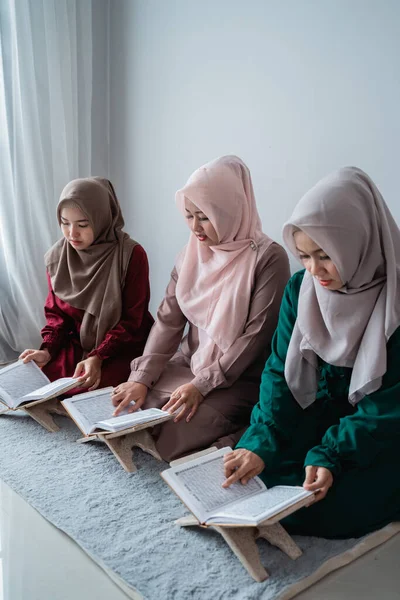 Tiga perempuan muda mengenakan jilbab membaca kitab suci Al-Quran bersama-sama — Stok Foto