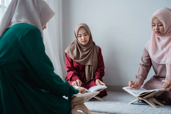 Tiga perempuan muda mengenakan jilbab membaca kitab suci Al-Quran bersama-sama — Stok Foto