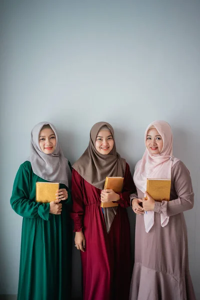 Tre hijab kvinnor smider hålla den heliga boken av Al-Quran — Stockfoto