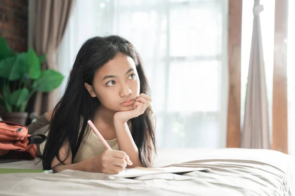 Ázsiai lány tanul és gondolkodik az ágyon — Stock Fotó