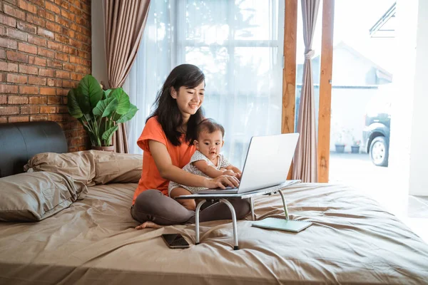 Asian woman working while taking care children — Stock Photo, Image