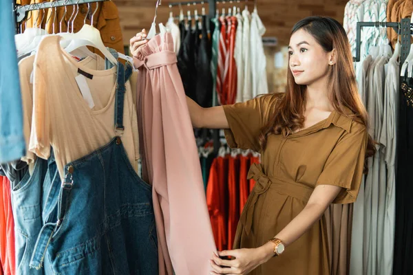 Donna guardando alcuni vestiti nel negozio di moda — Foto Stock