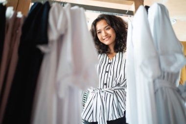 Moda mağazasında bazı kıyafetlere bakan bir kadın.