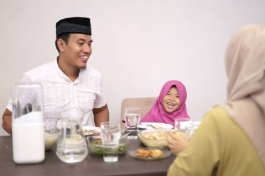 Adam kızı ve ailesiyle birlikte akşam yemeği yiyor.