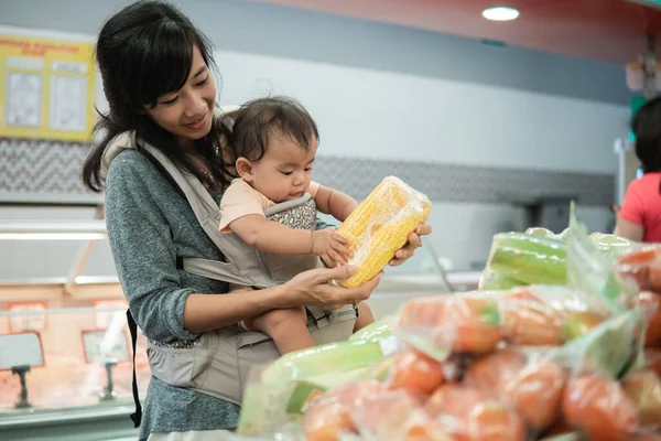 Aziatische vrouw dragen haar baby terwijl winkelen — Stockfoto