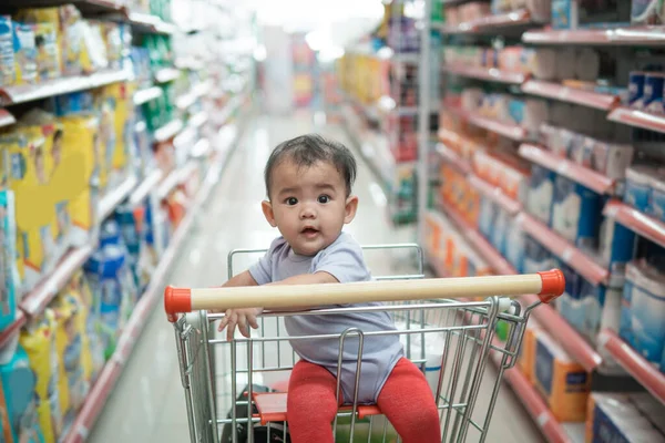 Happy infant baby sitting alone in shopping cart — Stock Photo, Image