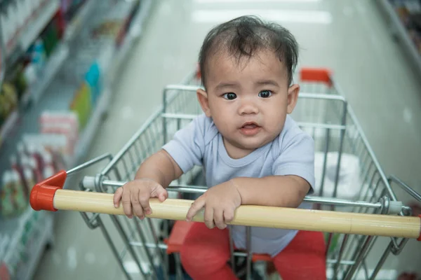 Bebé feliz sentado solo en el carrito de la compra —  Fotos de Stock