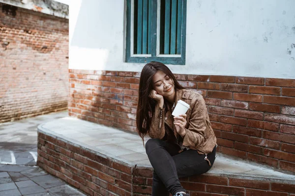 Vrouw zitten op de weg genieten van een kopje koffie — Stockfoto