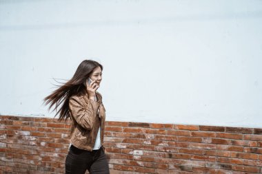 Kadın şehirde yürürken telefonla konuşuyor.