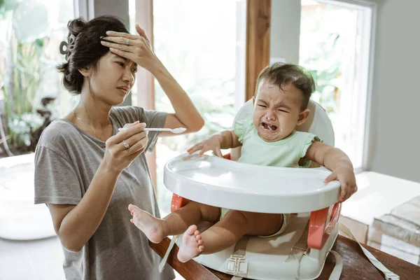 Stress mother while feeding her baby — Stock Photo, Image