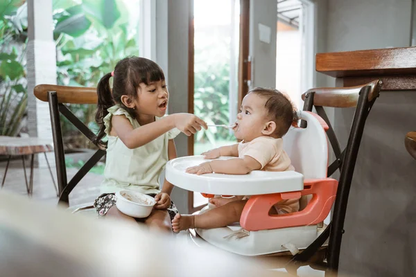 Сестра кормит младшую сестрёнку — стоковое фото