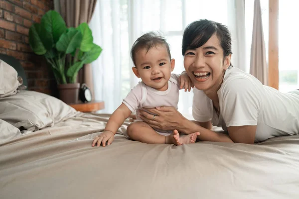 Madre giocare con il suo bambino sul letto — Foto Stock