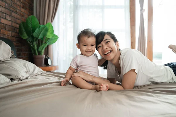 Madre jugando con su bebé en la cama —  Fotos de Stock