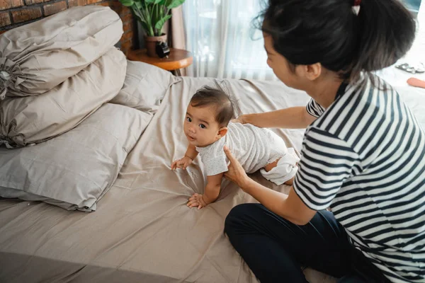 Moeder spelen met haar baby op het bed — Stockfoto