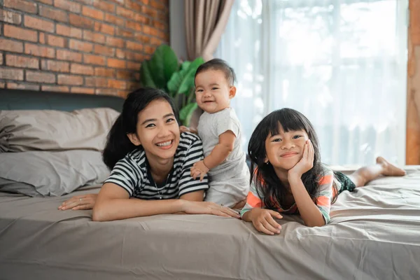 Mère et ses deux enfants couchés sur le lit — Photo