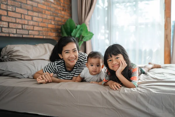 Mother and her two children laying on the bed — Stock Photo, Image