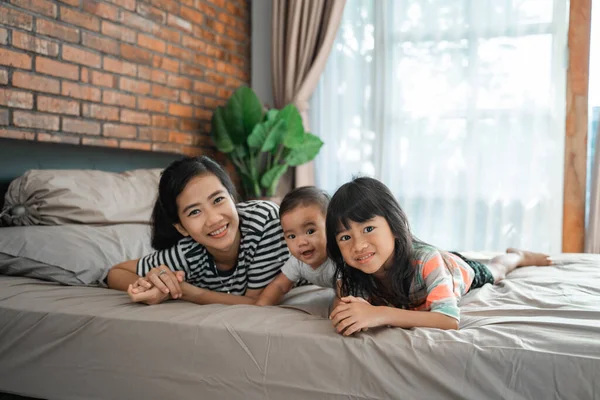 Madre y sus dos hijos acostados en la cama — Foto de Stock