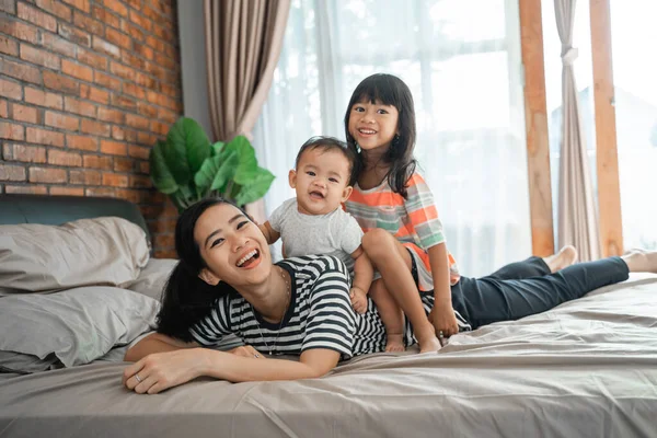 Children sitting on mothers back playing — Stock Photo, Image