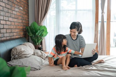 Annesi dizüstü bilgisayarı ve çocuğu yataktaydı.