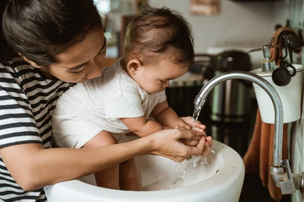 Мати допомагає своїй дитині помити руку — стокове фото