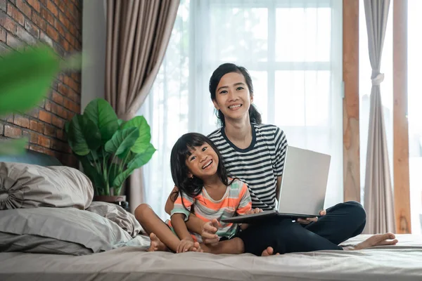 Anya laptoppal és gyermekével az ágyon — Stock Fotó