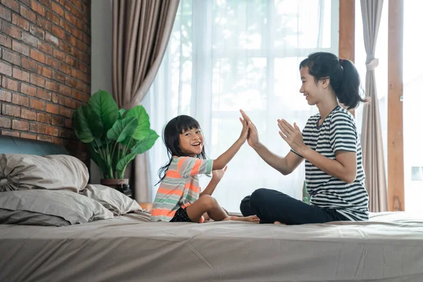 Matka a dítě hraje high five na posteli — Stock fotografie