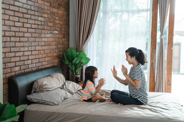 Мать и ребенок играют "дай пять" на кровати — стоковое фото